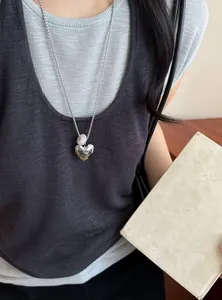 Close-up detail of a vintage silver heart necklace with a natural stone bead on a model.