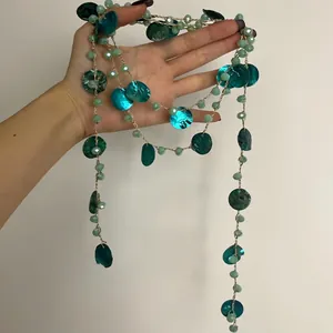 Dettaglio di una lunga collana di perle di conchiglia in stile etnico retrò in mano