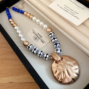 Detail view of a vintage necklace with ceramic beads and a hammered gold pendant.