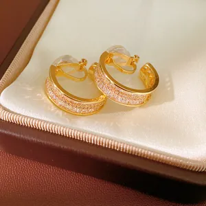 Close-up of elegant gold-plated hoop ear clips with sparkling crystal inlay in gift box