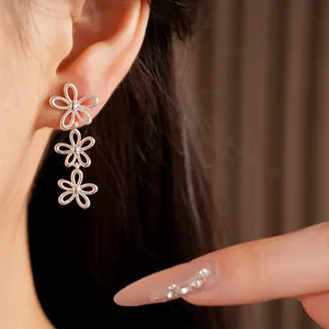 Close-up detail of silver-colored hollow flower earrings worn by an Asian model