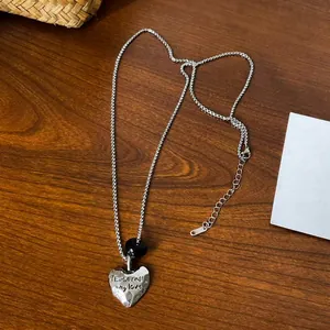 Detail of silver heart pendant necklace with 'Eternal my love' engraving and black bead