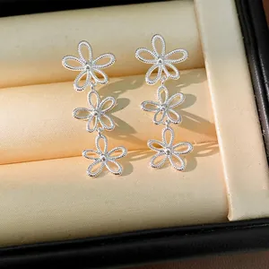 Close-up detail of silver hollow triple-flower drop earrings with textured rope finish