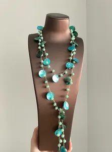 Dettaglio ravvicinato di una collana etnica con perle verdi e dischi di conchiglia