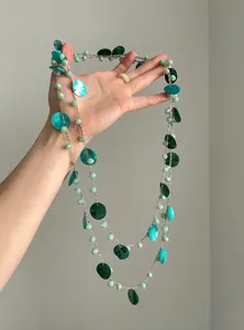Dettaglio ravvicinato dei dischi di conchiglia e perline verdi su una collana etnica