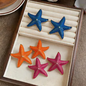 Detailed view of colorful oil-drop starfish earrings with pearl center in a jewelry tray