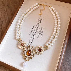 Vintage palace style double-strand pearl necklace with floral resin pendant detail.