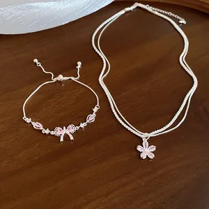Detailed view of sparkling zircon bowknot bracelet and five-petal flower necklace on a wood background