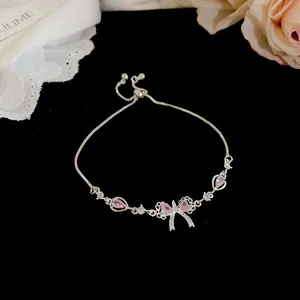 Detailed view of sparkling silver bow bracelet with pink zircons on elegant black velvet