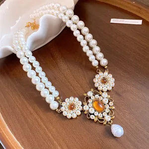 Macro view of vintage double-layer pearl necklace with intricate floral resin pendant detail.