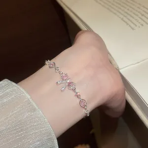 Sparkling silver bracelet with pink zircon bow flower design worn on woman's wrist