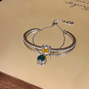 Luxury double-layer bracelet with zircon teardrop pendant on golden reflective surface