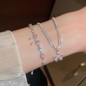 Close-up of sparkling zircon bow and flower charms on delicate silver bracelets