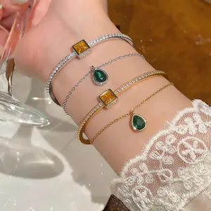 Detailed view of layered gold and silver bangles with emerald pear and yellow square stones