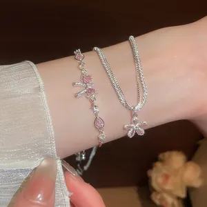 Detail view of sparkling pink zircon bow bracelet and delicate flower pendant chain