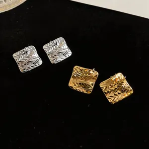 Dettaglio macro di orecchini a lobo quadrati placcati oro 18k con trama a rombi incisa