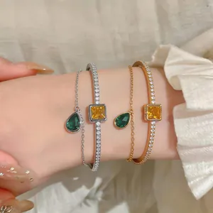 Close-up of luxury double-layer zircon bangle with green teardrop and yellow square stones