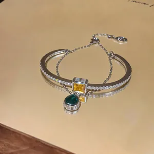 Detailed shot of a silver double-layer bracelet with emerald and yellow gemstones