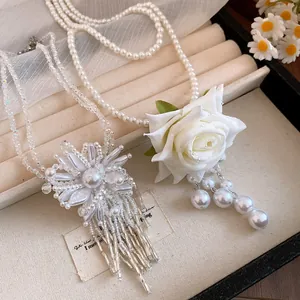 Detalle del elegante collar de perlas de doble capa con rosa de tela y colgantes de perlas