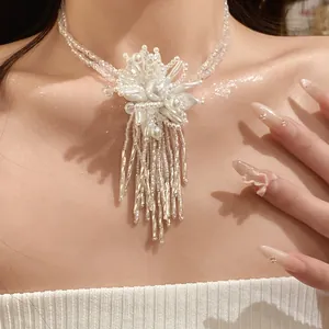 Primer plano de un collar de flores de cuentas blancas con flecos largos en el cuello