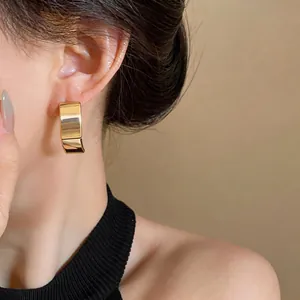 Zijaanzicht detail van elegante 18K vergulde minimalistische vierkante oorknopjes