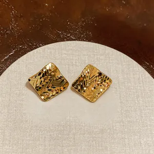 Vista dettagliata di orecchini a lobo a rombo placcati oro 18k con elegante trama diamantata.