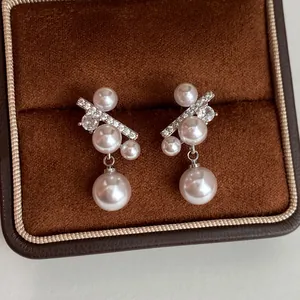 Dettaglio macro di eleganti orecchini in argento con perle e zirconi in scatola marrone.