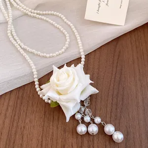 Vista detallada del elegante collar de perlas de doble capa con colgante de rosa blanca