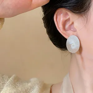 Primo piano di un orecchino ovale in argento con perla centrale e trama a raggiera