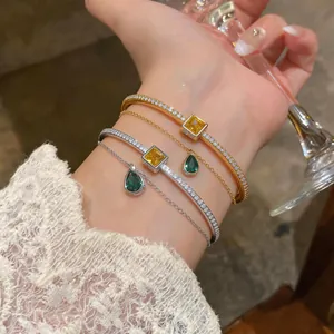 Close-up of elegant double-layer bracelets with yellow square and green teardrop zircon stones.