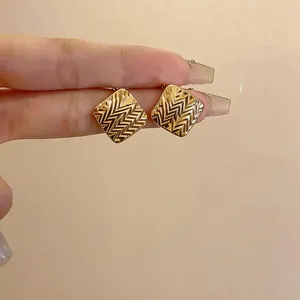Primo piano di orecchini a lobo placcati in oro 18k con un raffinato motivo a spina di pesce