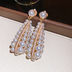 Eleganti orecchini vintage a goccia traforati con perle lucenti e zirconi brillanti.