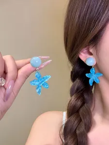 Primo piano dettagliato di orecchini pendenti a stella marina blu indossati da una modella