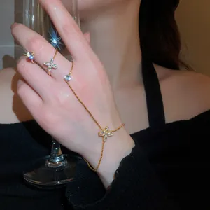 Elegant gold hand chain with zircon flower details worn by model holding glass