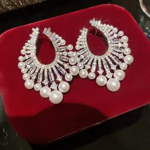 Primo piano di orecchini vintage a pendente con zirconi brillanti e perle bianche