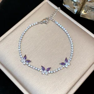 Detailed macro shot of silver butterfly bracelet with purple zircons on jewelry box.