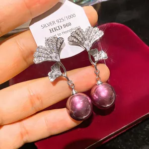 Dettaglio orecchini ginkgo con zirconi e perle viola pendenti su perni in argento