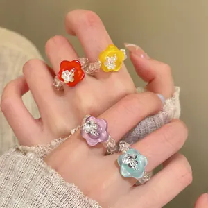 Nahaufnahme von bunten Harzblumen-Perlenringen an einer Hand im trendigen Dopamin-Stil.