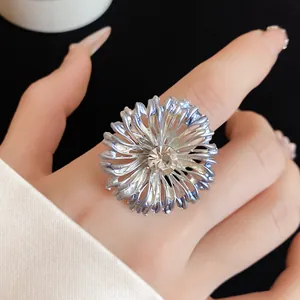Detalle de un elegante anillo floral azul metálico con un brillante cristal central decorativo.