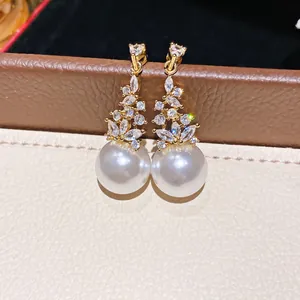Dettaglio di eleganti orecchini a goccia con perle e zirconi dorati e aghi in argento