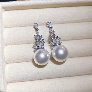Primo piano di eleganti orecchini a pendente con perle e zirconi in un portagioie