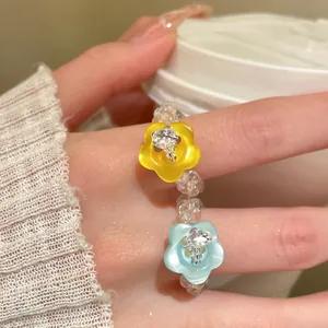 Detailansicht eines Perlenrings aus Harz mit gelben und blauen Blumenanhängern.