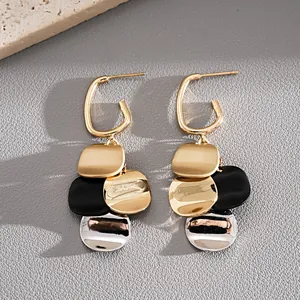Close-up detail of multi-color layered metal disk drop earrings with gold hoops