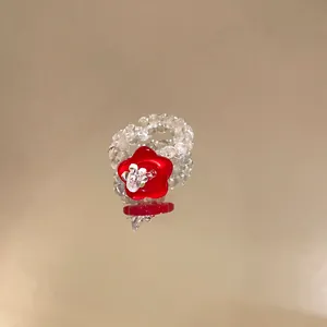 Detailaufnahme eines minimalistischen Rings mit roter Harzblume und Perlenband