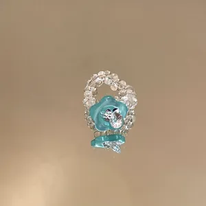 Detailaufnahme der Textur eines modischen Perlenrings mit blauer Blume aus Harz