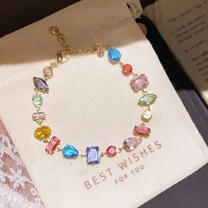 Close-up detail of a colorful zircon geometric link bracelet on a cream gift pouch