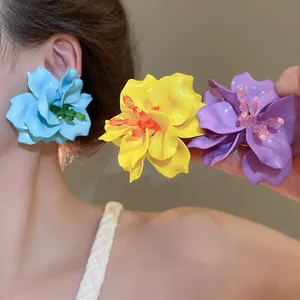 Detailed view of large 3D acrylic flower earrings in blue, yellow, and purple colors