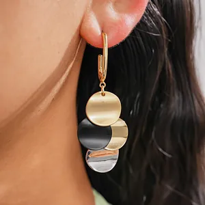 Close-up of gold-plated drop earrings with overlapping multi-color circular sequins.