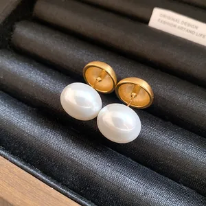 Primo piano di orecchini a lobo in oro spazzolato con eleganti perle bianche
