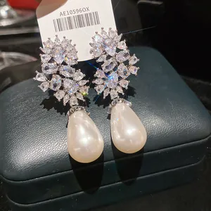 Primo piano di orecchini pendenti di lusso con zirconi scintillanti e perle a forma di pera
